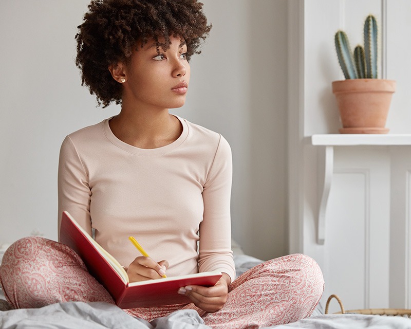 Young black woman feeling anxious on her bed