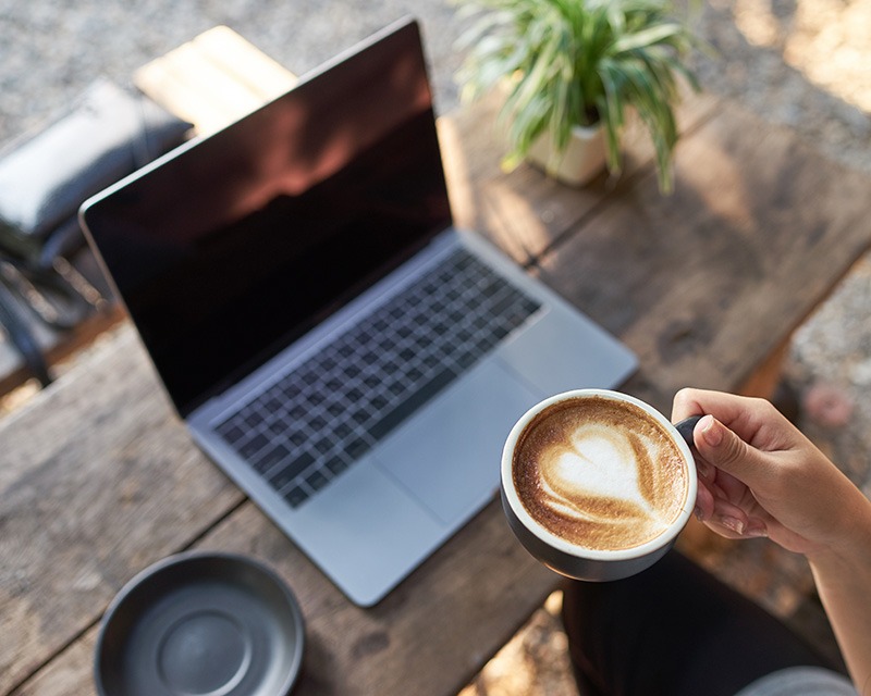 Woman with a latte in front of a laptop for depression therapy in Houston