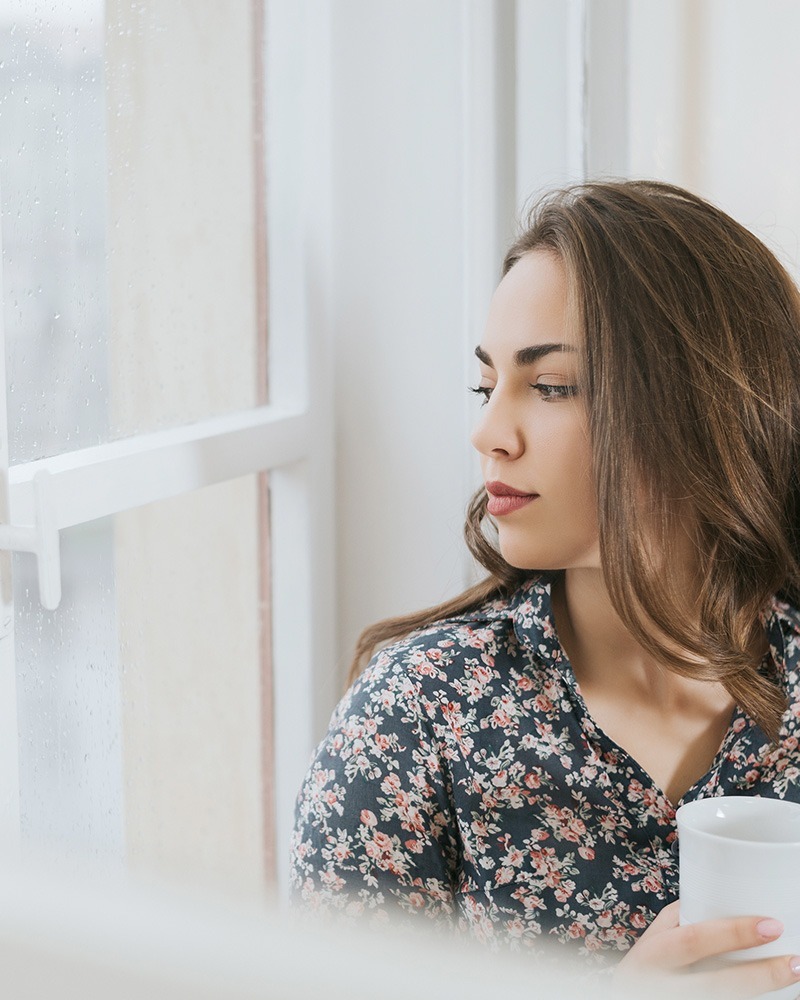 Woman looking out the window in the rain depression therapy texas