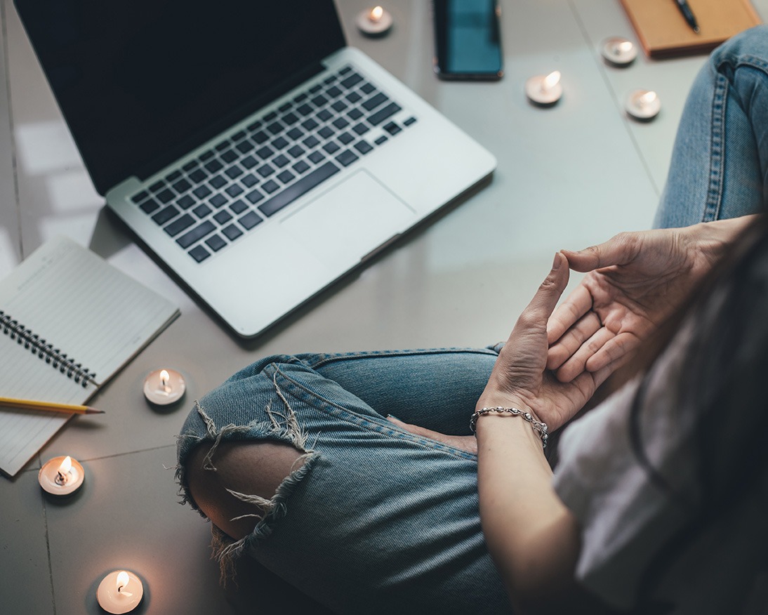 Woman sitting on the floor in front of a laptop for online trauma counseling in Texas